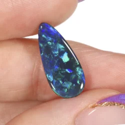 2.84ct natural black opal teardrop cabochon held between fingers at an angle, displaying vivid green and blue play-of-colour with large mosaic patterning against a dark body tone, Lightning Ridge Australia