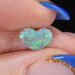 1.19ct solid dark opal heart held between fingers in close-up, displaying brilliant electric green colour play across the surface, Lightning Ridge Australia