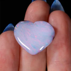 14.75ct solid boulder opal carved into a heart shape, held between fingers, displaying soft pastel pink and blue play-of-colour, natural untreated boulder opal from Winton Queensland Australia