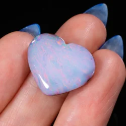 14.75ct natural boulder opal heart cabochon resting in a palm, showing sweeping pastel pink, lavender and blue colour play across a milky white base, Winton Queensland Australia