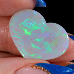 Neon green and aqua fire in heart-shaped black opal, side view