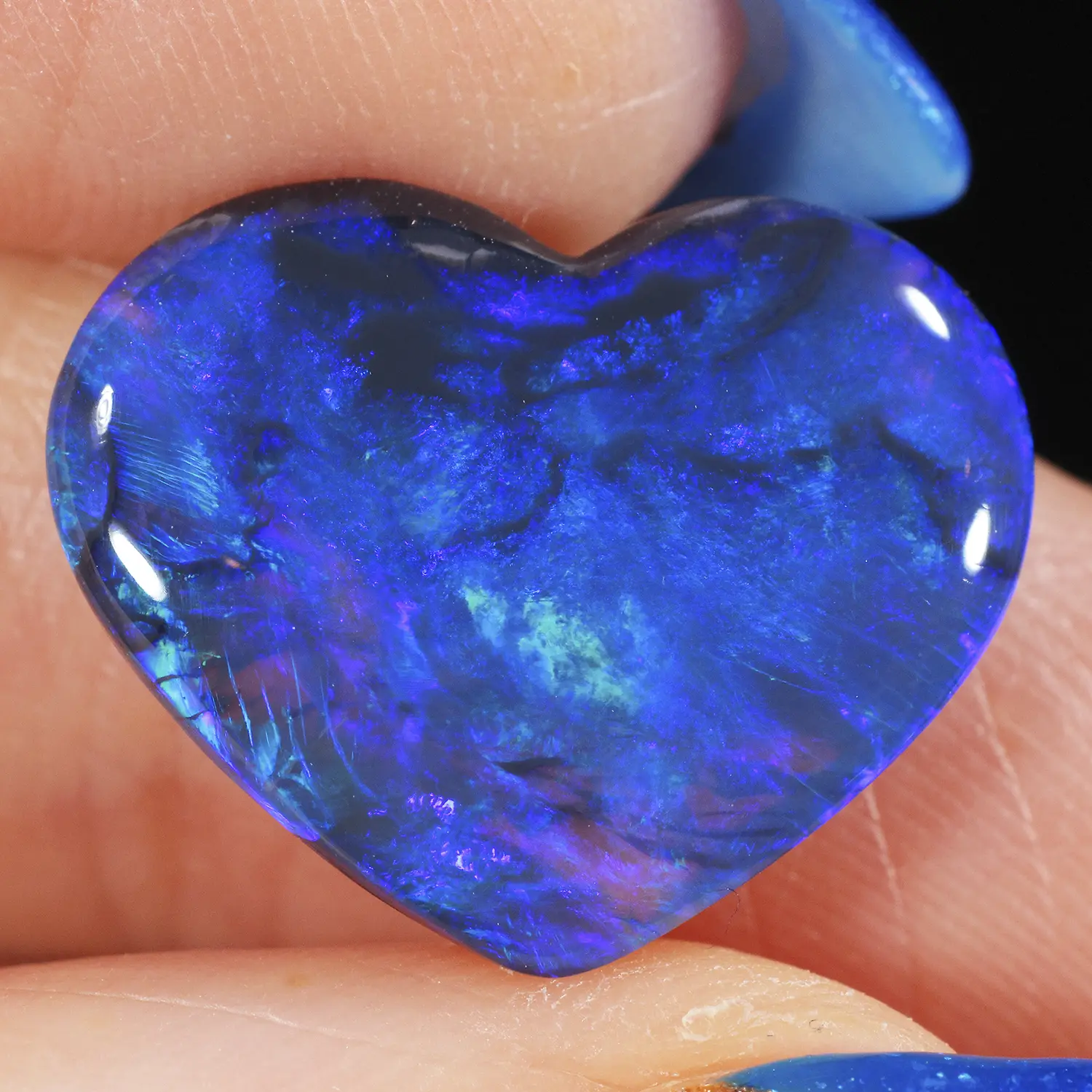 5.26ct solid black opal heart in close-up, showing sweeping deep blue, green and violet play-of-colour with fine feather patterning against a dark body tone, Lightning Ridge Australia
