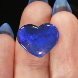 5.26ct solid black opal heart resting on a fingertip, showing vivid deep blue and violet play-of-colour across a dark translucent body, Lightning Ridge Australia