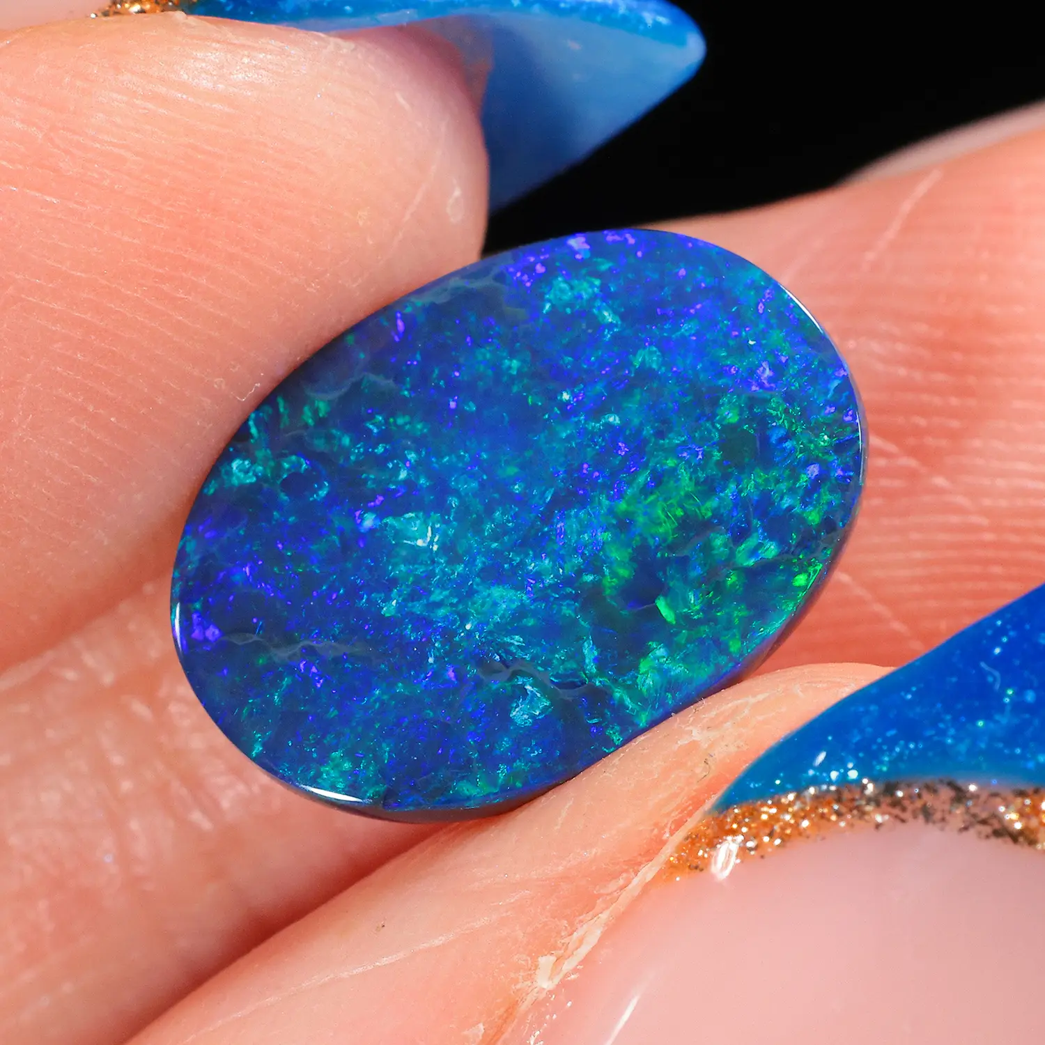 Natural oval shape black opal gemstone on fingers, sourced from Australia