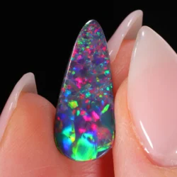 Teardrop opal between fingers with visible bright fire