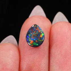 teardrop black opal with intense red and green fire on fingertip