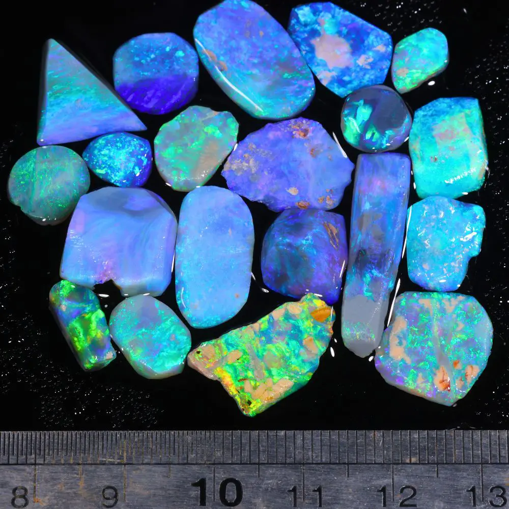 Lightning Ridge gem opal rubs parcel displayed with ruler showing size reference and vibrant blue green fire across stones