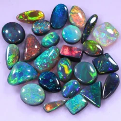 15ct Lightning Ridge opal wholesale jewelers parcel of 25 polished cabochons from Australia with green, teal, red, and blue fire. Mix of black, dark, and crystal opals. Natural, untreated.