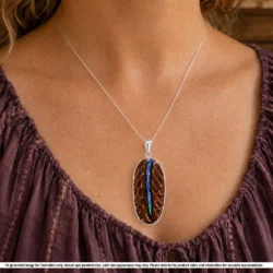 Natural Australian boulder opal pendant shown worn on a silver chain with blue green opal seam, oval matrix and sterling silver setting