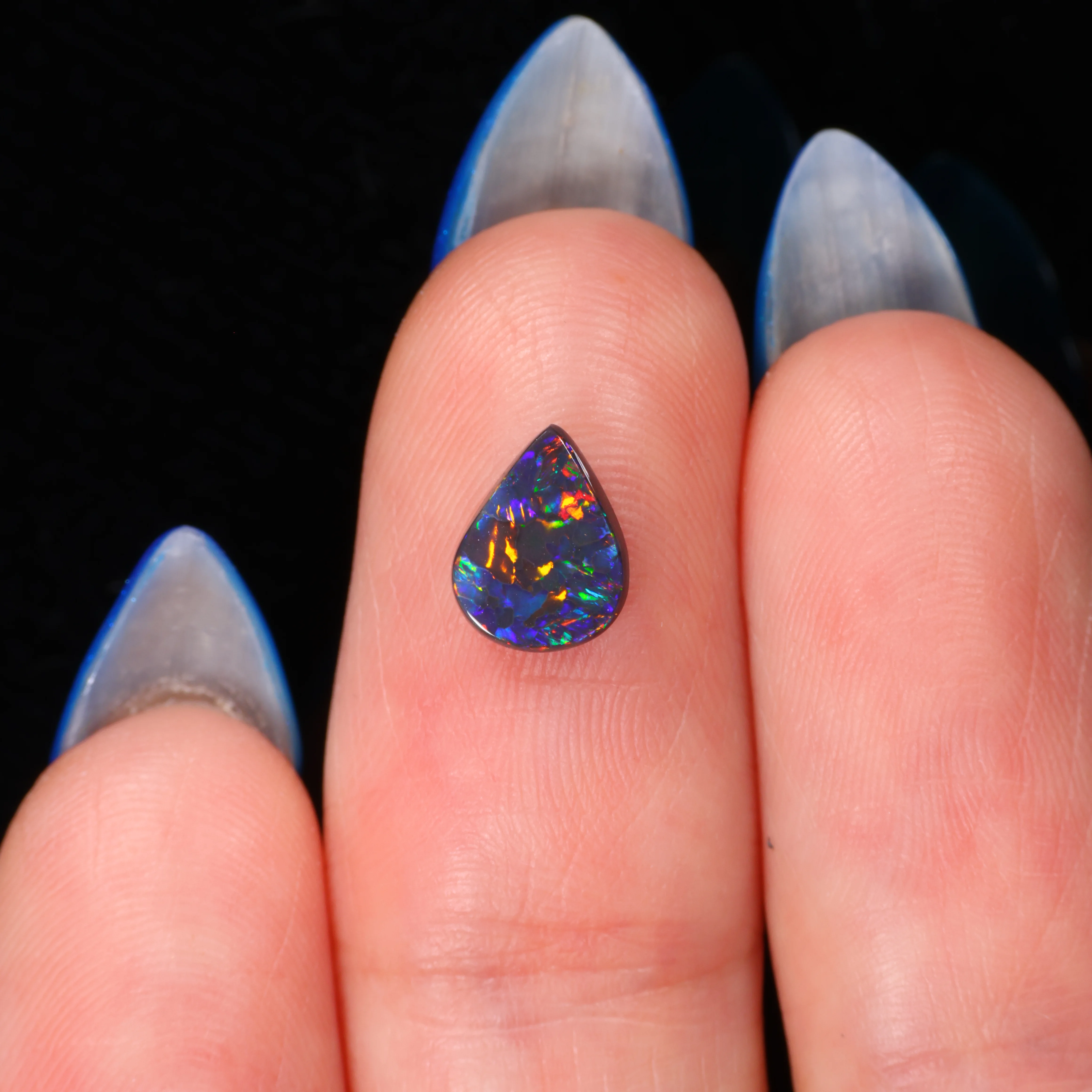 black-opal-pear-cabochon-finger-display-0-55ct-8x6mm-opal-galaxy