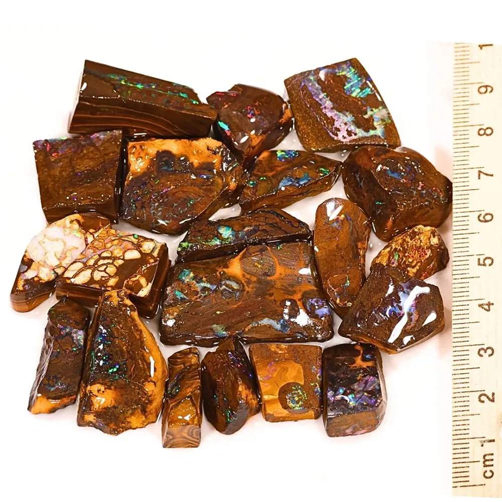 94g Boulder Opal matrix rubs from Winton Australia showing 20 natural pieces with rainbow color beside a ruler