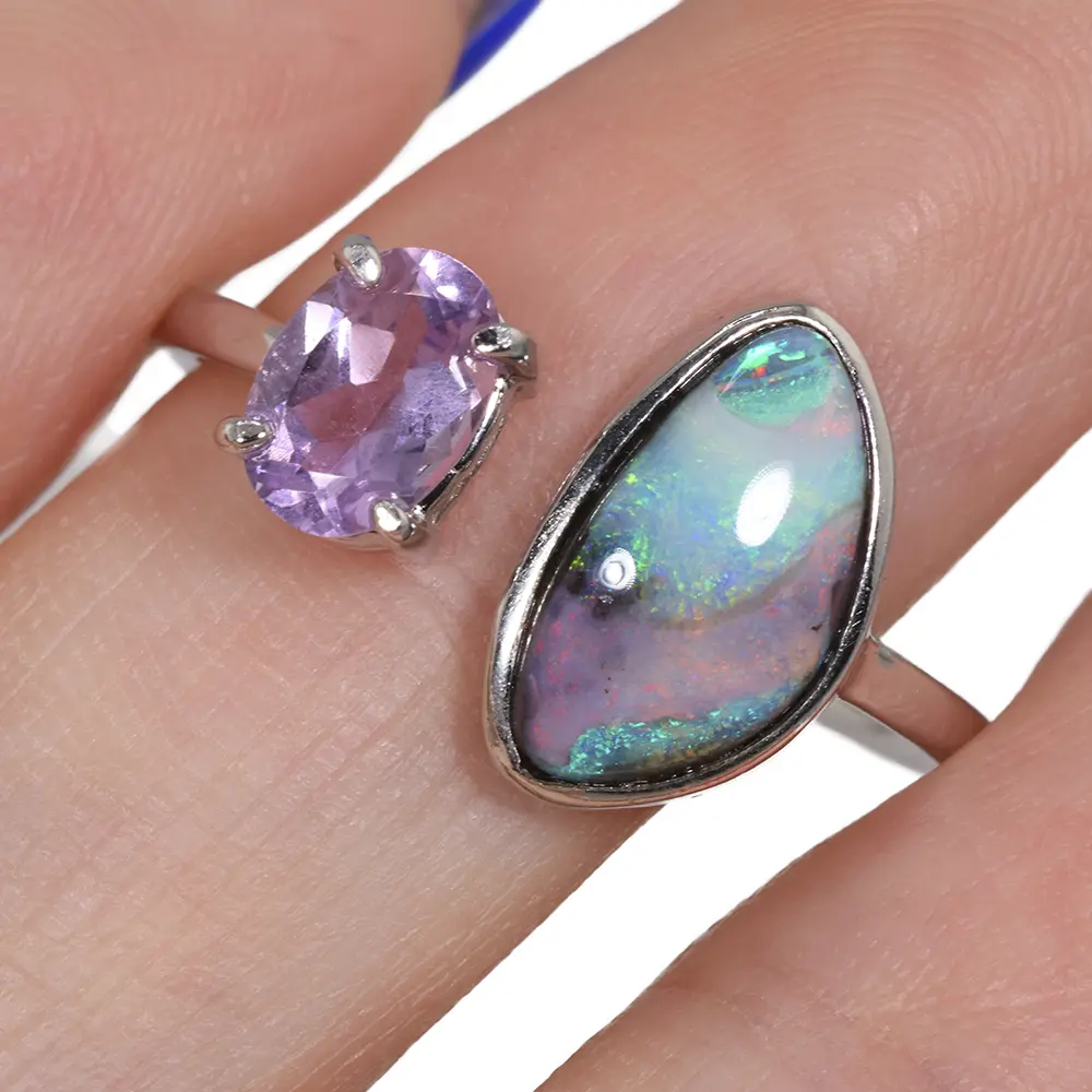 Natural Australian boulder opal and purple amethyst adjustable silver colored ring worn on a finger showing green blue and red opal colors
