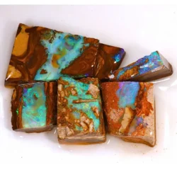Close up of five Australian Boulder Opal rubs showing bright turquoise and green play of color with natural brown ironstone and sandstone matrix.