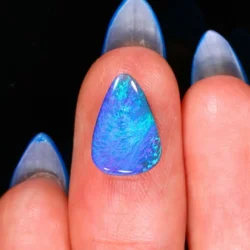 Natural Lightning Ridge black opal 1.68ct teardrop gemstone showing vibrant blue and green color on finger for scale.