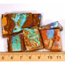 Five natural Winton Boulder Opal and Hard Sandstone Opal rubs weighing 53 grams with turquoise, aqua blue and green colors beside a ruler for size reference.