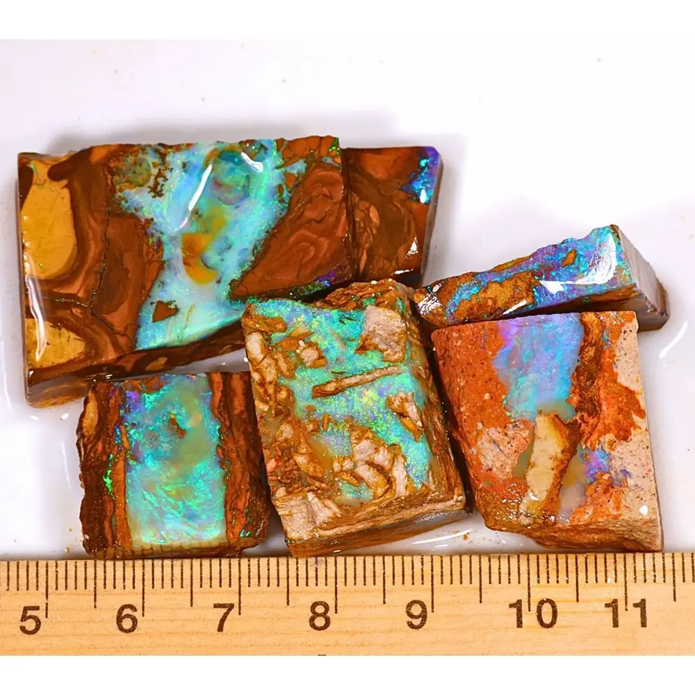 Five natural Winton Boulder Opal and Hard Sandstone Opal rubs weighing 53 grams with turquoise, aqua blue and green colors beside a ruler for size reference.